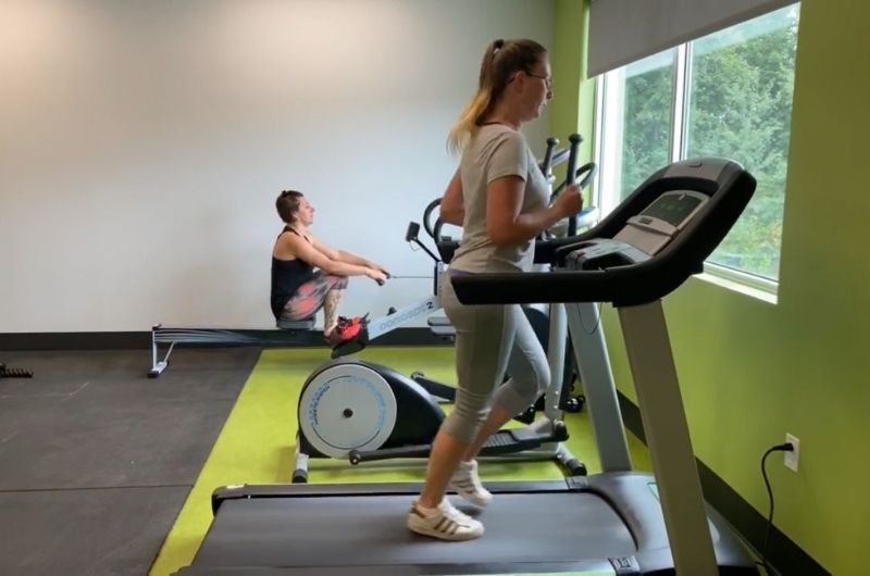 Deux filles s'entraînent dans un gym privé. Une cours sur un tapis roulant et l'autre s'entraîne au rameur