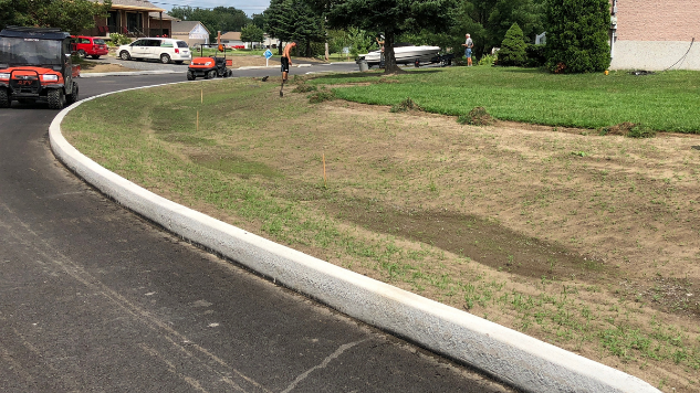 Une noue engazonnée est en construction sur l'emprise d'une rue dans un quartier résidentiel peu dense