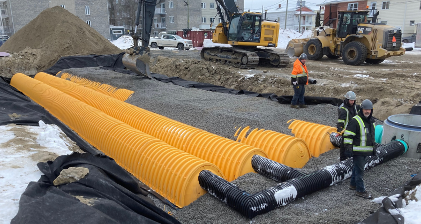 Du personnel de chantier se tiennent près de chambres d'infiltration avant le remblaiement