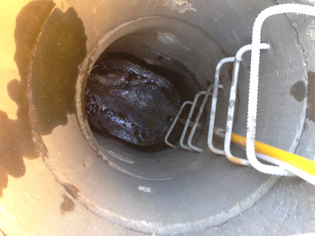 Intérieur d'un regard d'égout encrassé par accumulation de graisses et sédiments industriels