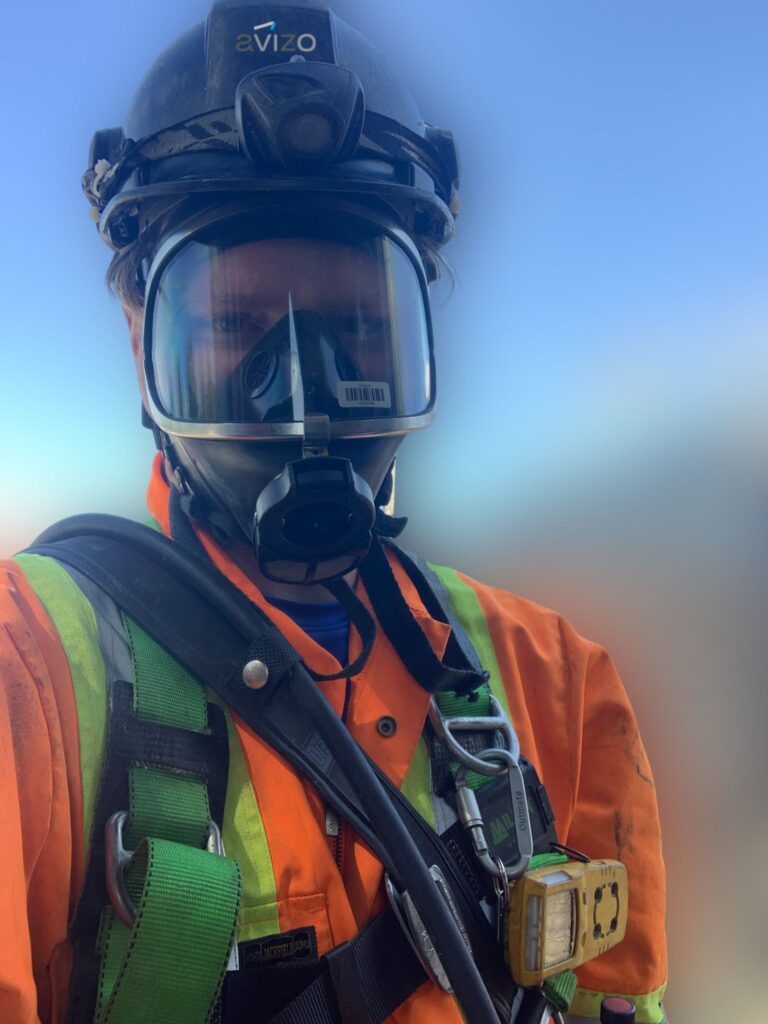 Municipal worker in full H₂S protective gear in the field